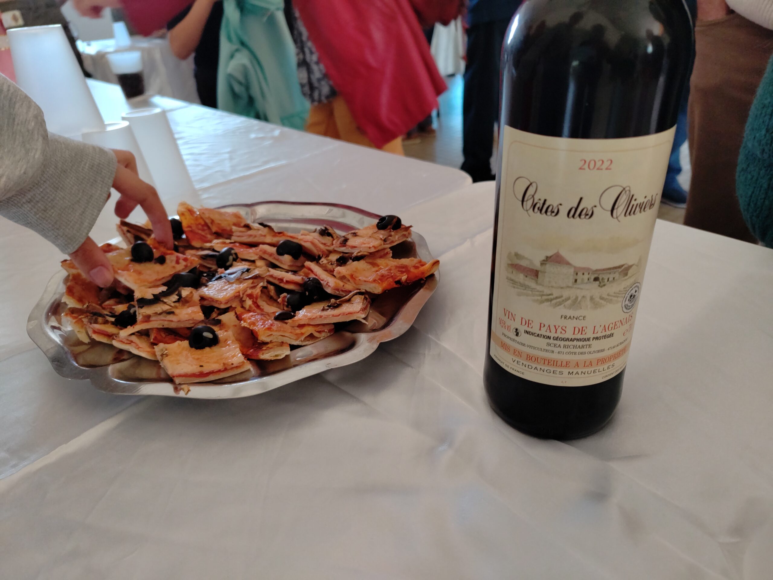 Une main saisissant une part de pizza au pot de l'amitié le 8 mai 2026 à Frespech
